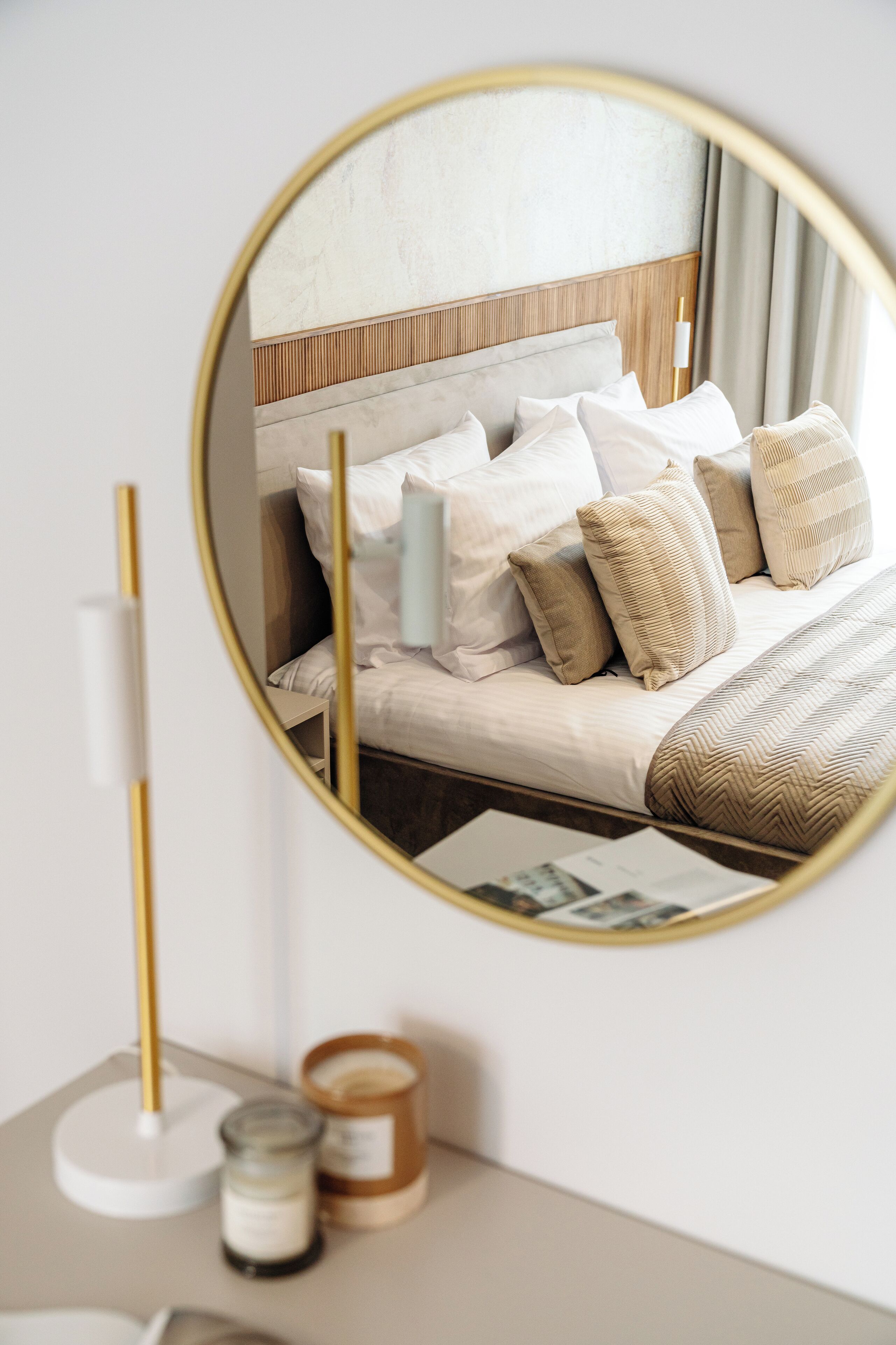 Une chambre à coucher comprenant un lit, une table de chevet, un miroir et une lampe fixée au mur.