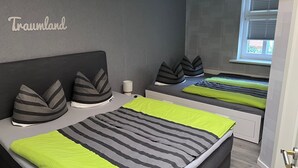 Un dormitorio con cama, almohadas, una mesita de noche y una ventana.