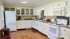 A kitchen with white cabinets, a refrigerator, a stove, and a microwave. - Cozy Country Cottage (Culleoka)