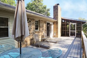 A patio with outdoor furniture, a brick house, and a glass door leading to a covered area.