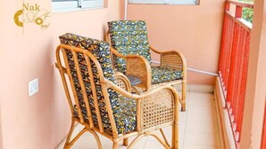 Two wicker chairs with patterned cushions on a balcony with a red railing. - 2 Bedroom Cozy Apartment. (Accra)