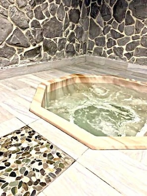 A stone wall surrounding a hot tub area with a mosaic tile floor.