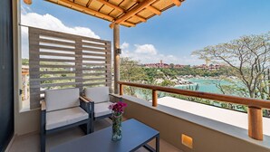 A balcony with a view of a coastal landscape, a wooden pergola, a sofa, a table, and a vase with flowers. - Endless Ocean Views and Direct Beach Access (Huatulco)