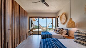 A modern bedroom with a large bed, a desk, and a view of the outdoors. - Endless Ocean Views and Direct Beach Access (Huatulco)