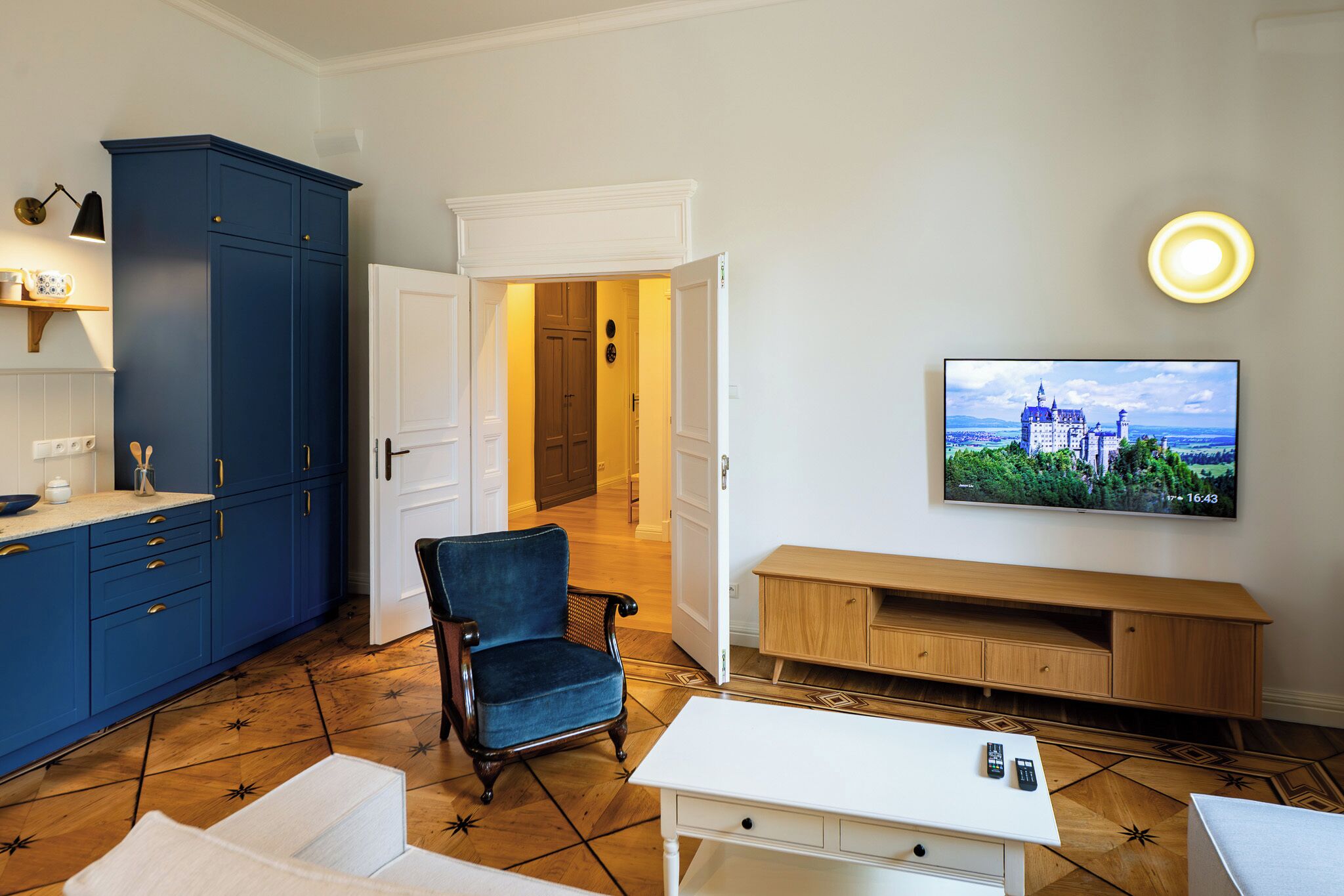 Ein modernes Wohnzimmer mit Fernseher, einem blauen Schrank, einem Holzschrank und einem Sessel.