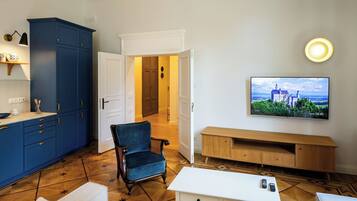 Ein modernes Wohnzimmer mit Fernseher, einem blauen Schrank, einem Holzschrank und einem Sessel.
