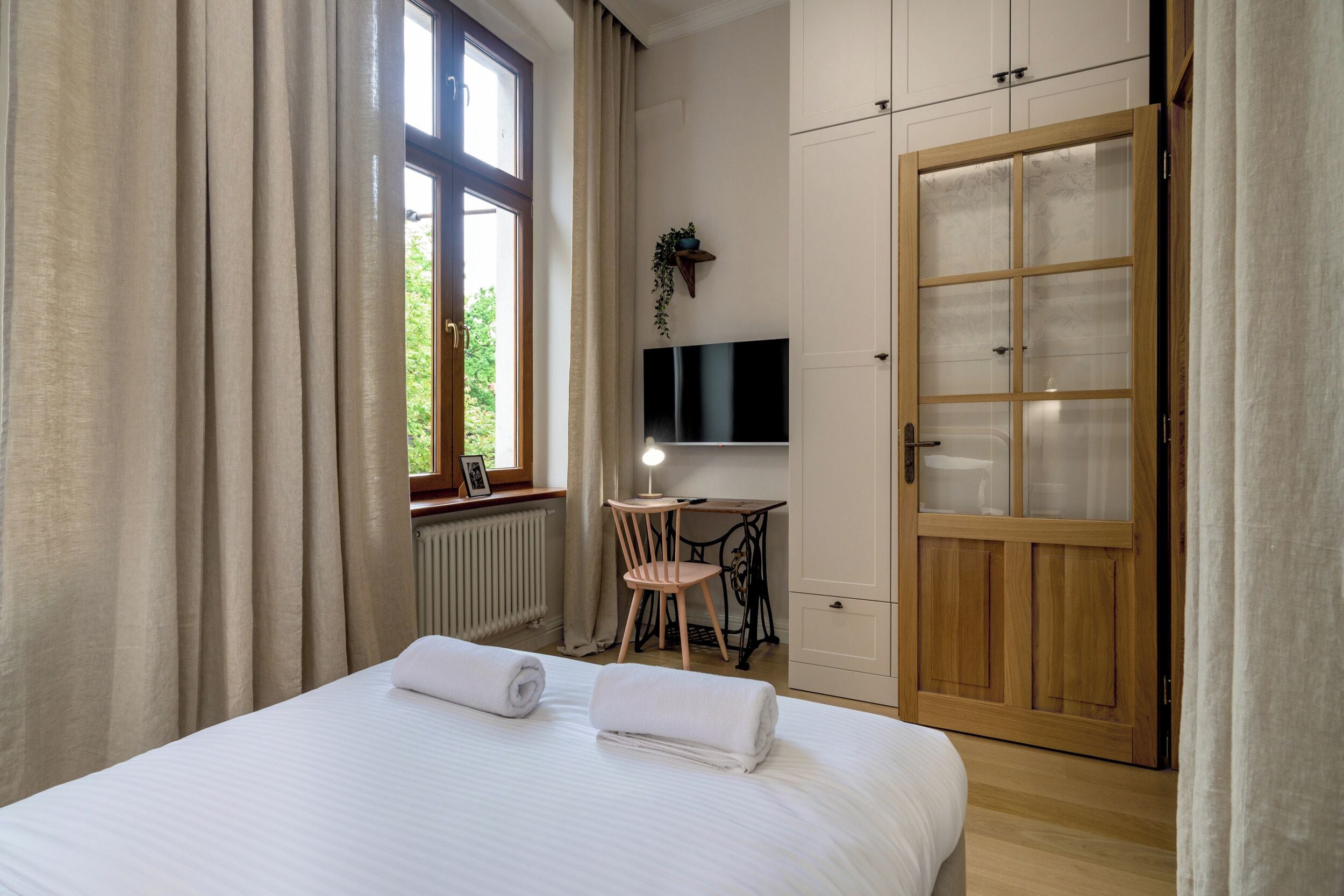 A bedroom with a bed, a desk, a chair, a TV, and a wardrobe.