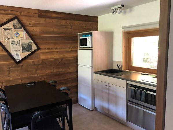 A compact kitchen with a refrigerator, microwave, dishwasher, and a window.