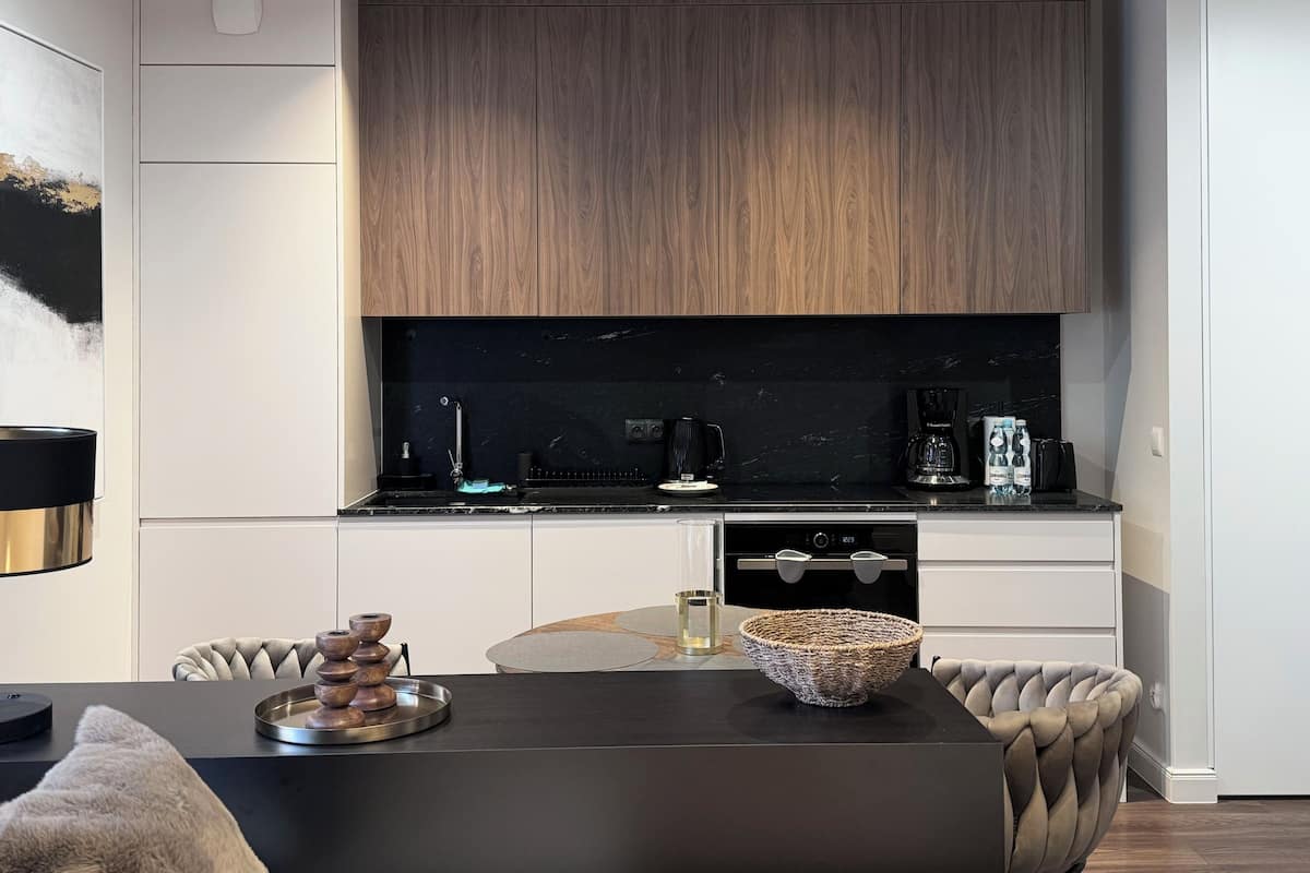 A modern kitchen with dark wood cabinets, a black countertop, and a dining area with a round table and chairs.