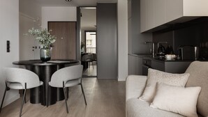 Une cuisine moderne avec des meubles de couleur sombre, un coin repas avec une table ronde et des chaises, et un canapé agrémenté de coussins.