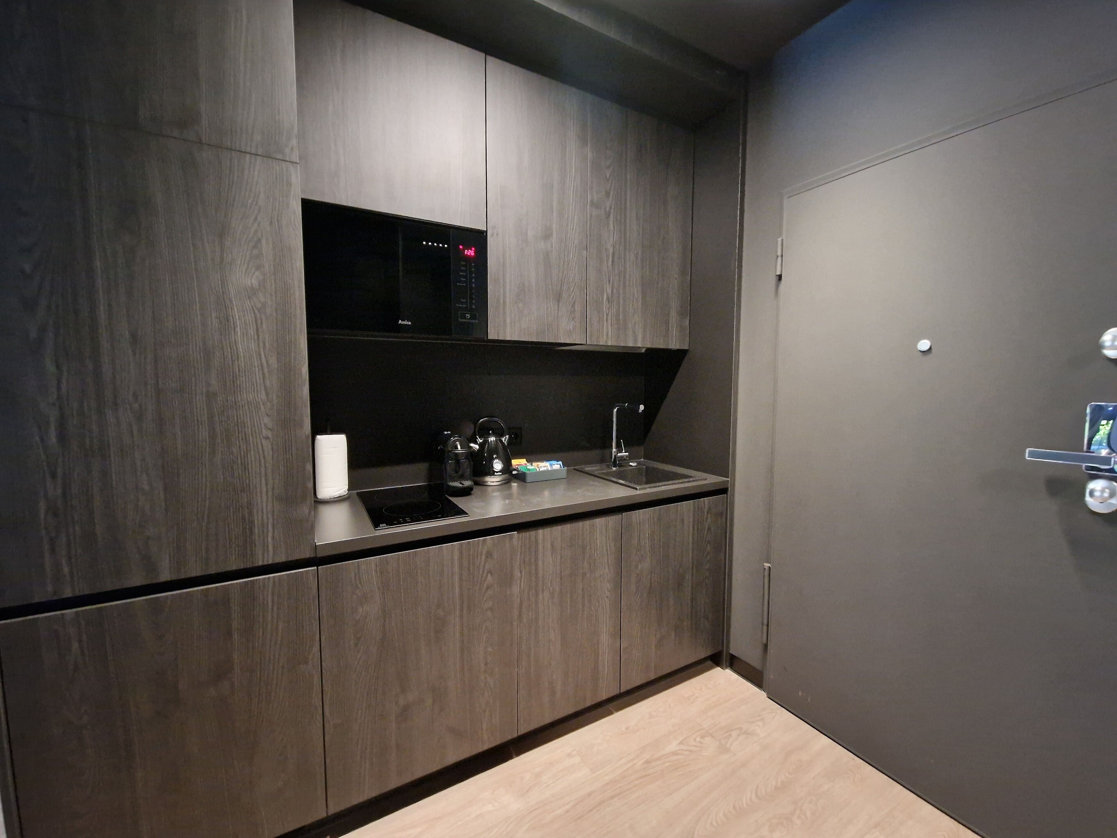 A modern kitchen with a built-in microwave, coffee maker, and sink.
