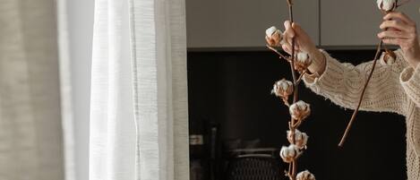 A person arranging a cotton branch in a black vase on a wooden table.