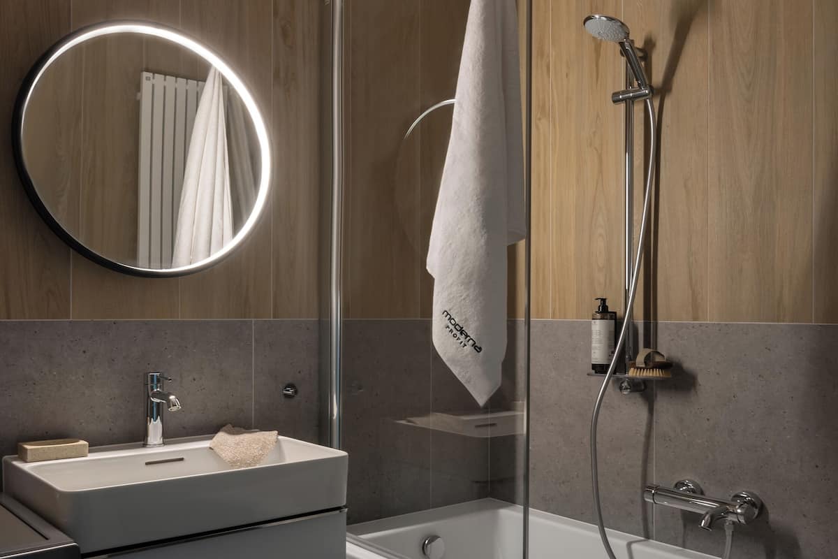 A modern bathroom with a glass shower enclosure, a built-in sink, and a vanity with drawers.