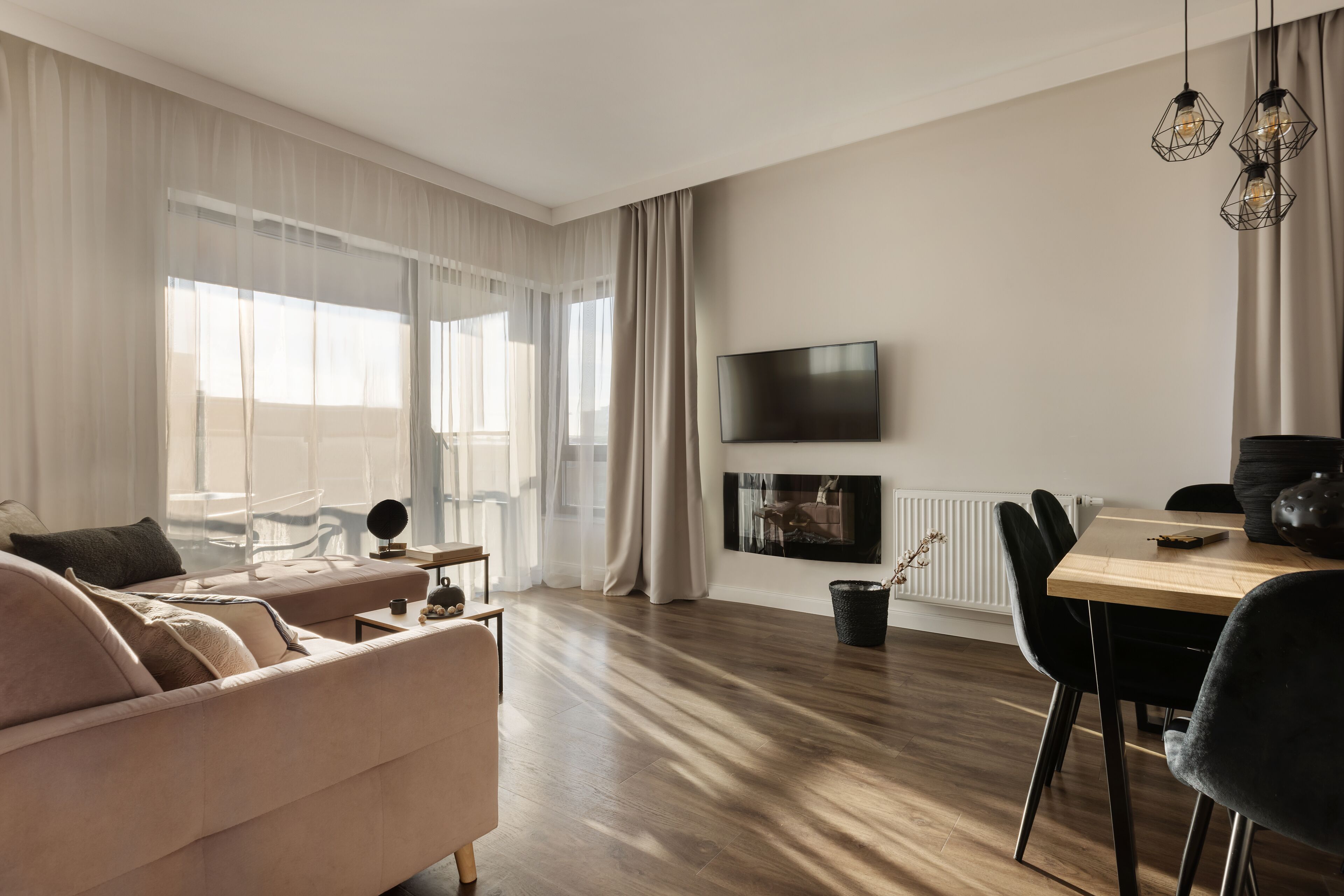 Un salon moderne comprenant un canapé, une table à manger, des chaises, un téléviseur et une cheminée.