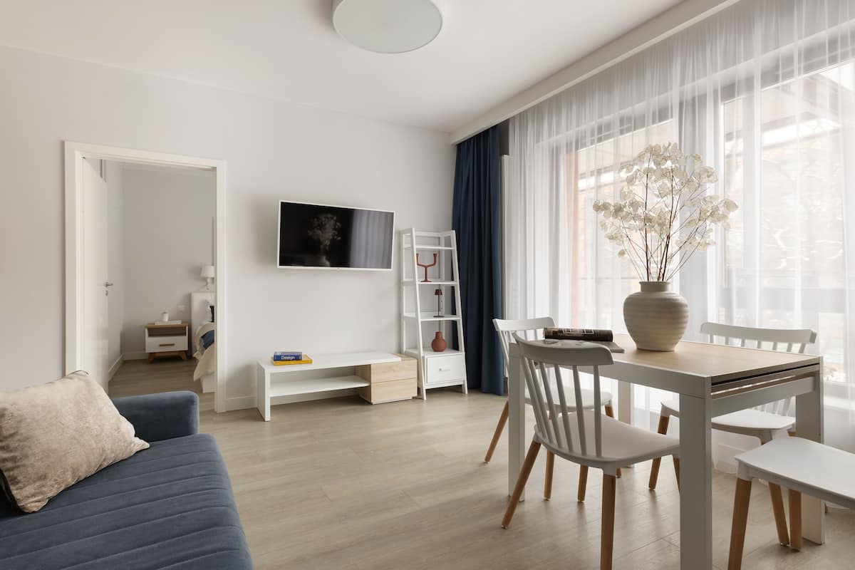 A modern living room with a sofa, dining table, chairs, a TV, and a bookshelf.