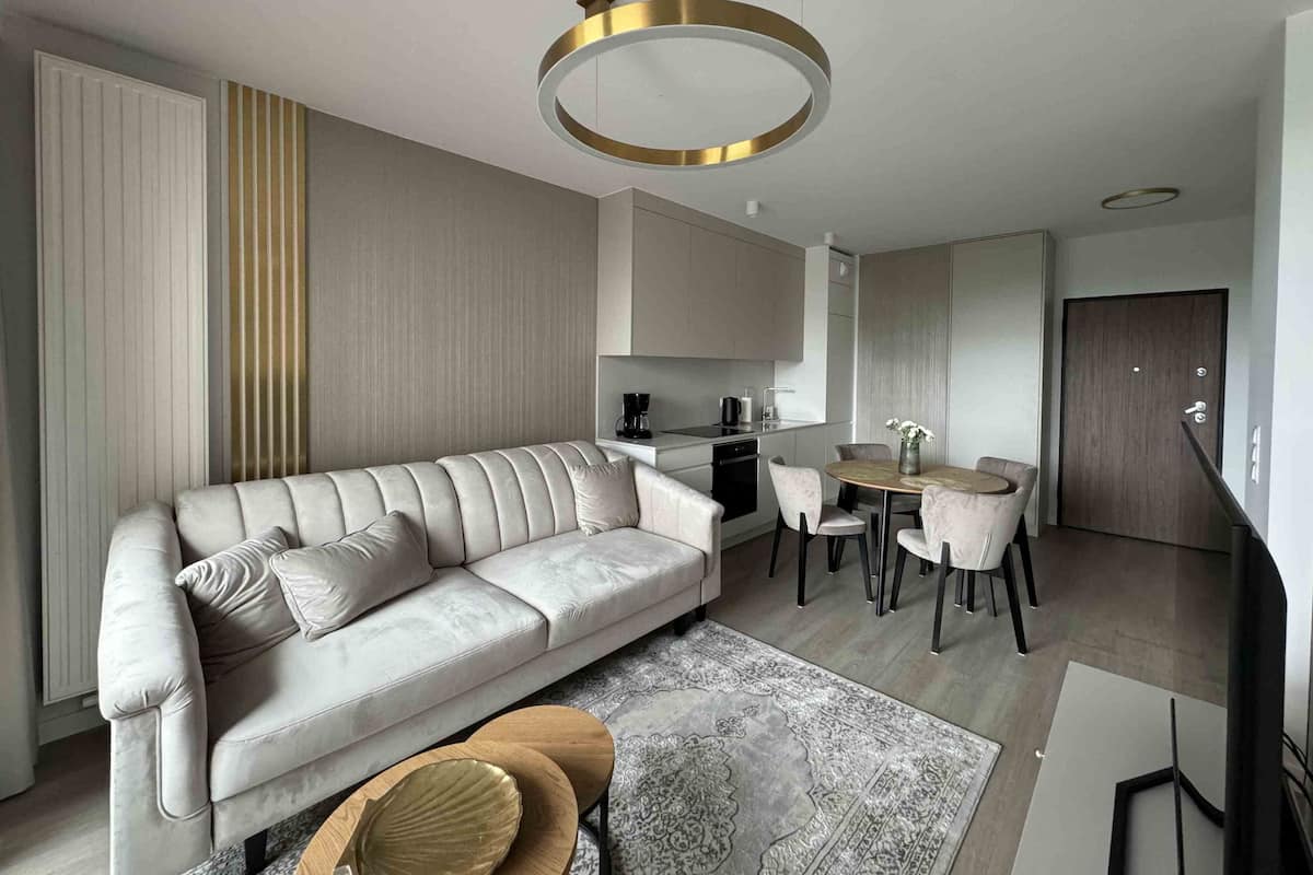 A modern living room with a sofa, coffee table, and dining area.