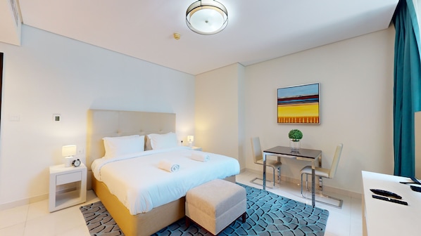 A hotel room with a bed, bedside tables, a desk, and a chair.