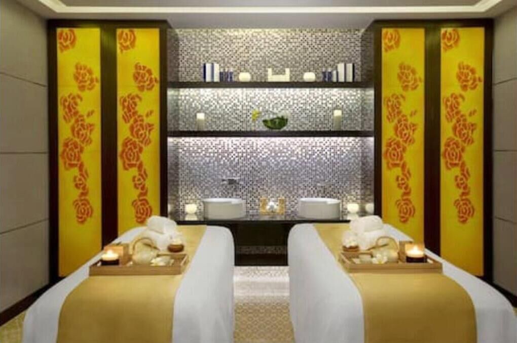 Um quarto de spa com duas camas, um espelho e painéis decorativos.