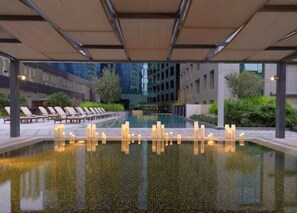 A pool area with lounge chairs and a water feature. - GreenFuture - Charming Studio in the Vibrant Business Bay (Dubai)