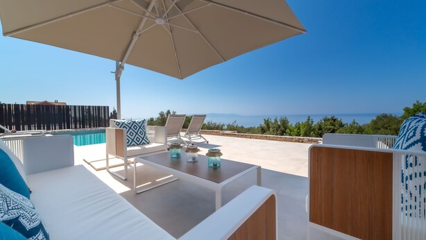 Una terraza con piscina, sillas de descanso y vista al mar.