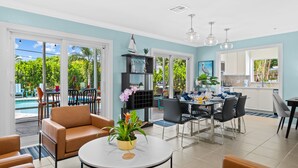 A spacious living area with a dining table, comfortable seating, and a view of the outdoor pool. - Peaceful Tropical Escape with Heated Pool Near Fort Lauderdale Beach! (Fort Lauderdale)