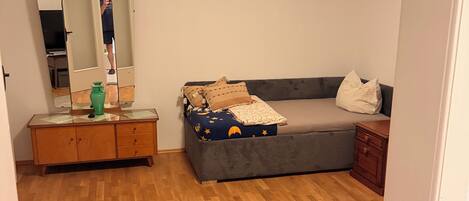 Ein Zimmer mit einem Bett, einem Schminktisch, einem Spiegel und einem runden Teppich.