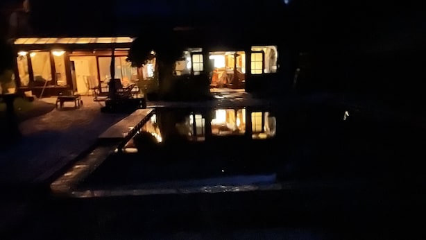 Vista nocturna de un edificio con una piscina reflectante al frente.
