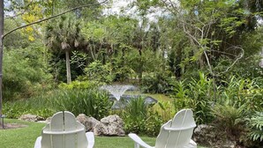 Due poltrone Adirondack in un giardino con uno stagno e vegetazione rigogliosa.