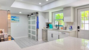 Una cucina moderna con una grande isola, mobili bianchi e una finestra che si affaccia sul verde.