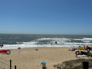 Una playa con gente tomando el sol y una bandera en la arena.