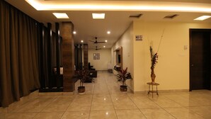 Un vestíbulo de hotel de diseño moderno, con suelo de baldosas, un mostrador de recepción y un cartel de 'No Fumar'.