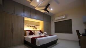 Habitación de hotel moderna con cama grande, armario empotrado, ventilador de techo y aire acondicionado.
