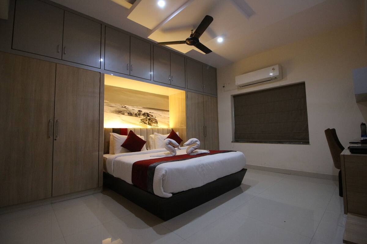 Een moderne hotelkamer met een groot bed, inbouwkast, plafondventilator en airconditioning.