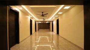 Un pasillo de hotel con ventilador de techo, iluminación empotrada y un piso de baldosas brillantes.