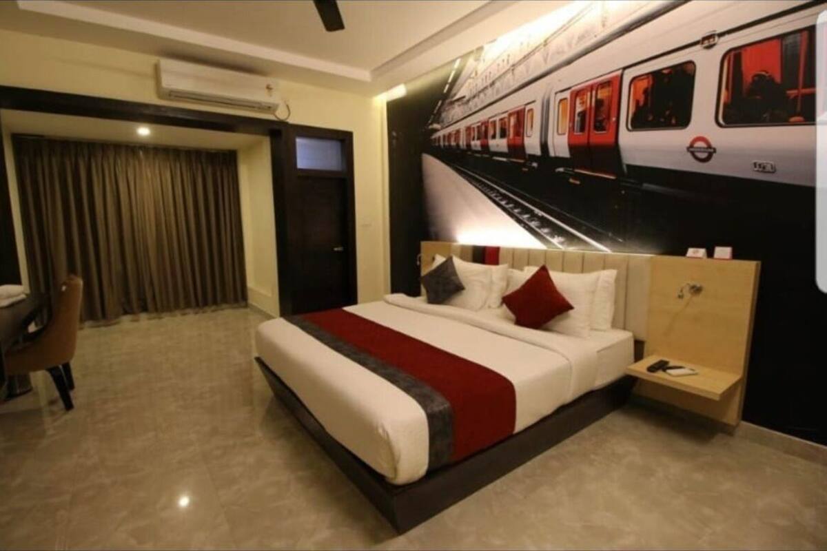 Een hotelkamer met een bed, een bureau, een stoel, een nachtkastje en een tv aan de muur.