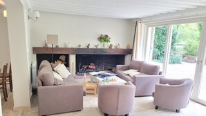 A living room with a fireplace, sofas, a coffee table, and a view of the outdoors.