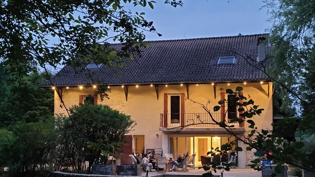 A two-story house with a stone wall and a balcony.