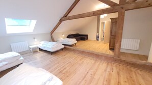 A loft bedroom with wooden beams, a skylight, a sofa, and a desk.