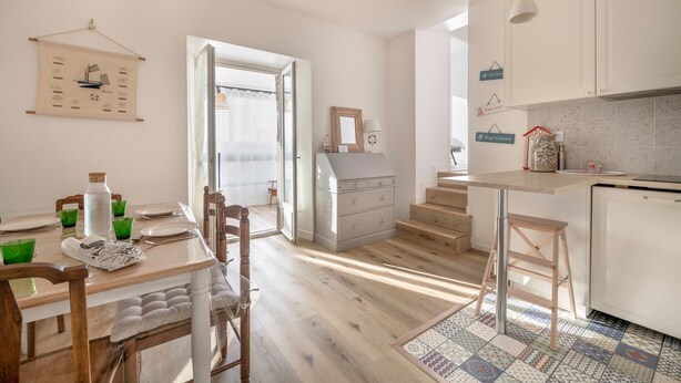 Una cucina moderna con mobili bianchi, un tavolo da pranzo in legno e un tappeto a motivi.