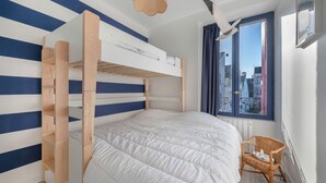 Camera con letto a castello e vista sugli edifici attraverso una finestra.