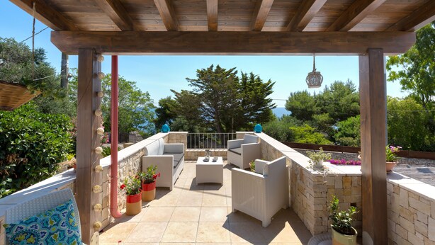 Une terrasse extérieure avec des poutres en bois, des murs en pierre et des plantes en pot.