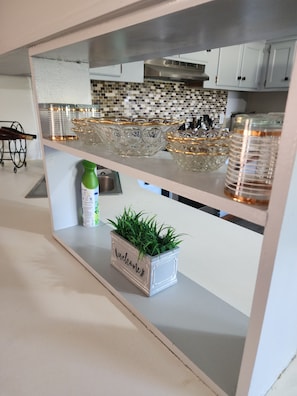 A kitchen with a white countertop, a decorative glass bowl, a green bottle, and a welcome planter. - Georgie's Getaway! Beautiful stay on 6 acres just minutes from the lakeside (Fort gibson)
