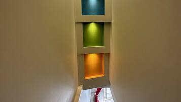 Una escalera estrecha con barandilla que conduce a un rellano con ventana.
