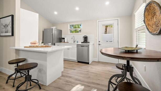 A compact kitchen with white cabinetry, a central island, and a round table with stools. - SoHo Suite by Brightwild | Steps to SoHo! (Tampa)
