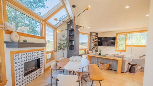 Amplia sala de estar con chimenea, comedor y cocina con televisor.