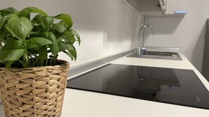 A modern kitchen with a woven basket containing green basil plants, a stainless steel sink, and a black countertop. - Tower Gombito's Apartment (Bergamo)