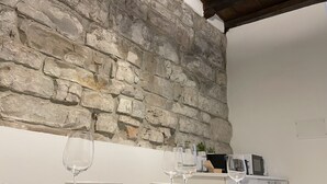 A dining area with stone walls, white table, and woven placemats. - Tower Gombito's Apartment (Bergamo)