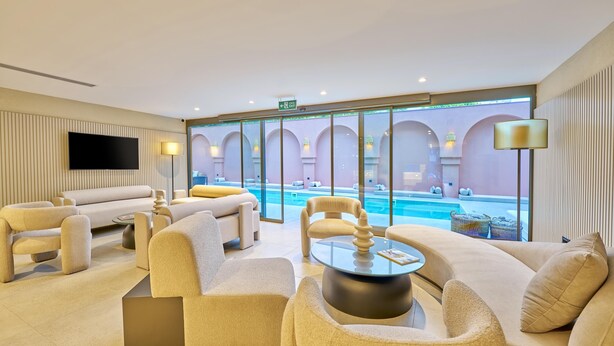 Recepció d'hotel moderna amb vista a la piscina, seients confortables i una televisió de pantalla plana.
