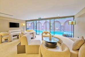 A modern hotel lobby with a pool view, comfortable seating, and a flat-screen TV. - La Maja Hotel  (Antalya)