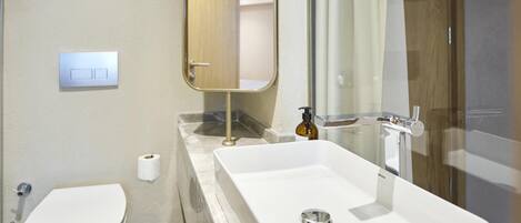 A modern bathroom with a white sink, a toilet, and a mirror.